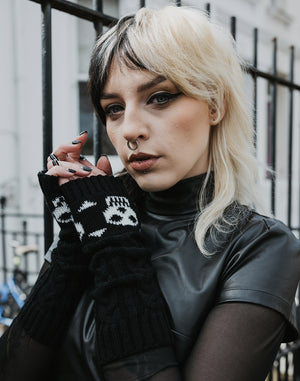Gothic model wearing chunky knit black gloves with white skull and crossbones